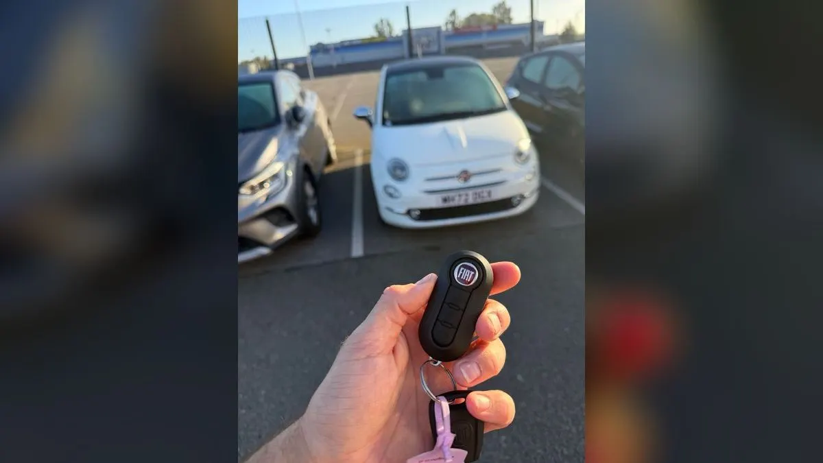 New Fiat 500 flip key held up in front of the white 2023 Fiat 500 Hybrid it was programmed to