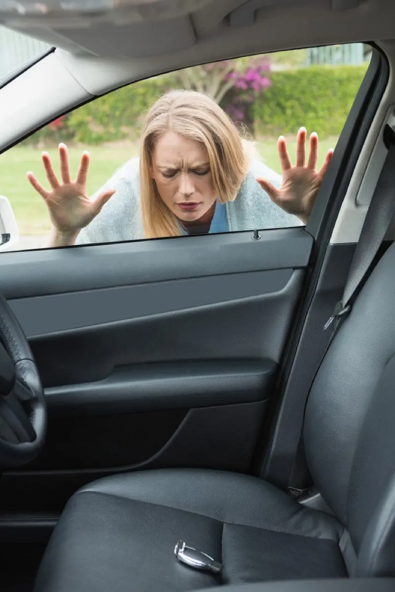 Driver looking through a car window at keys left on the seat