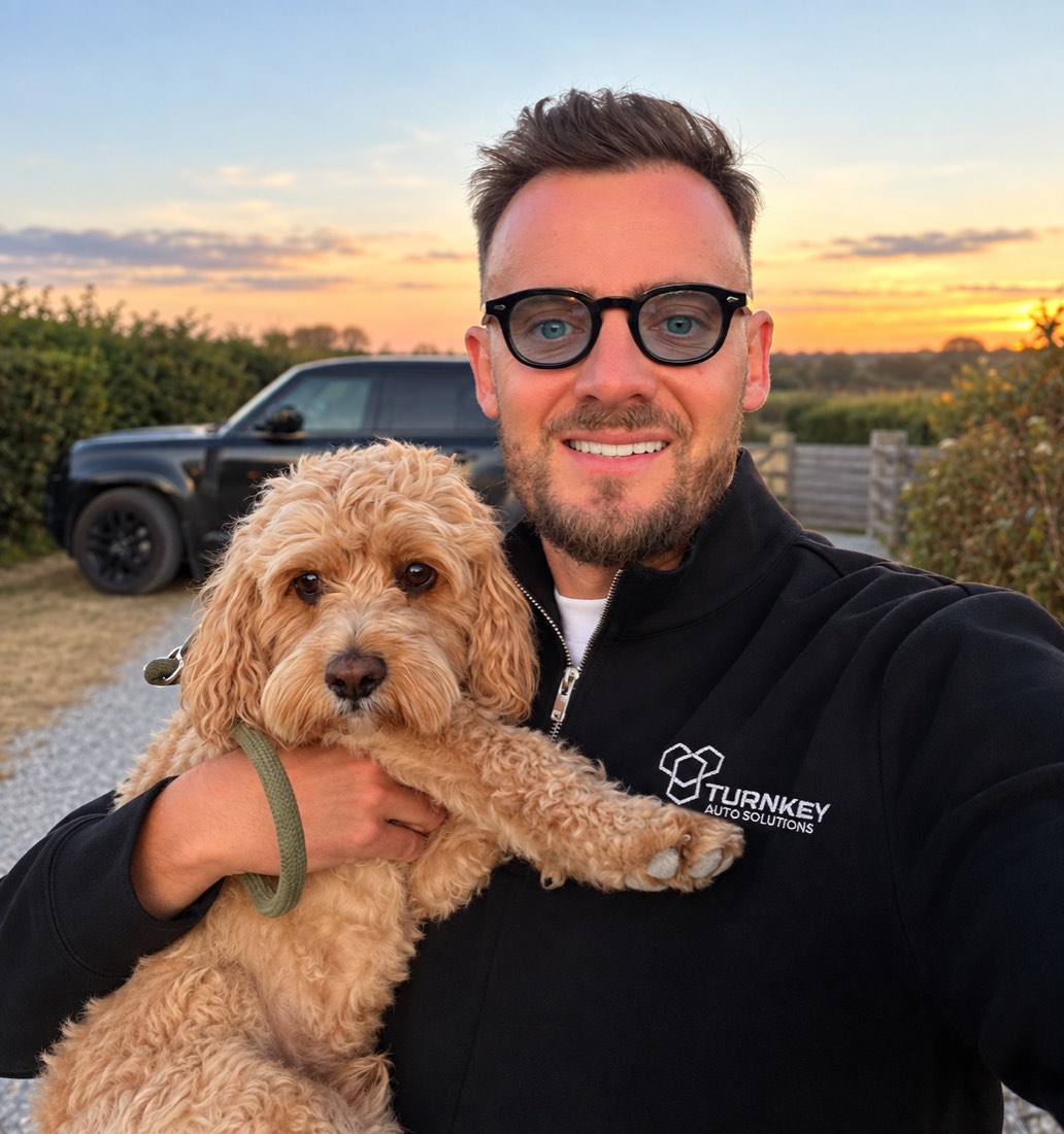 Thomas from Turnkey Auto Solutions holding his dog Humphrey at sunset